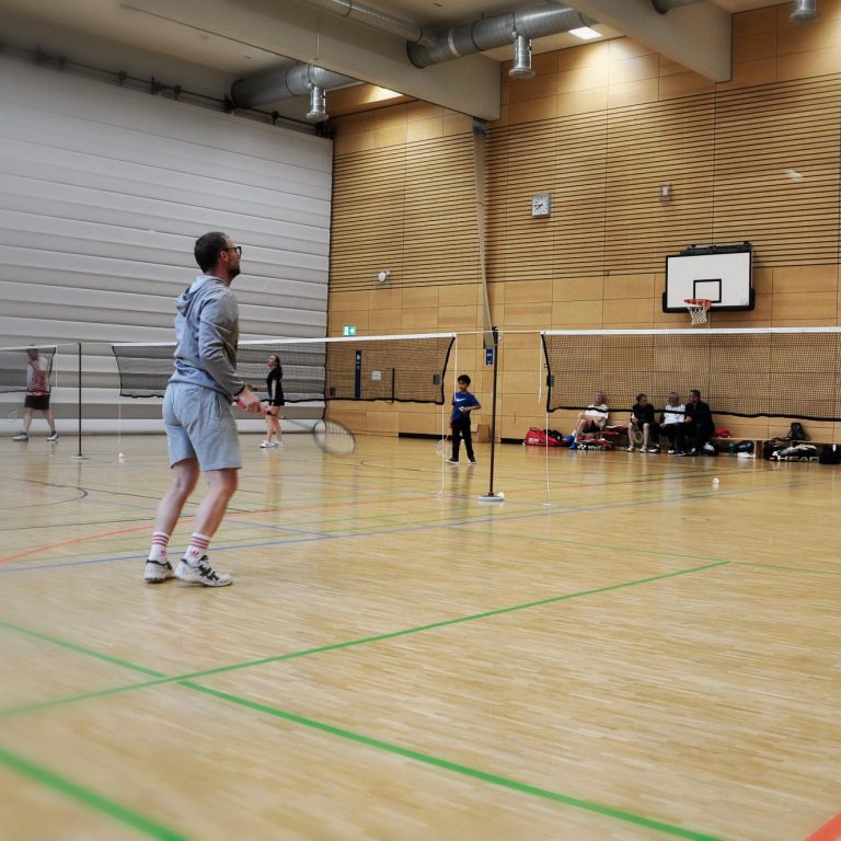 Trainingssituation mit mehreren Spielern auf Spielfeldern verteilt in einer Sporthalle mit Holzboden.